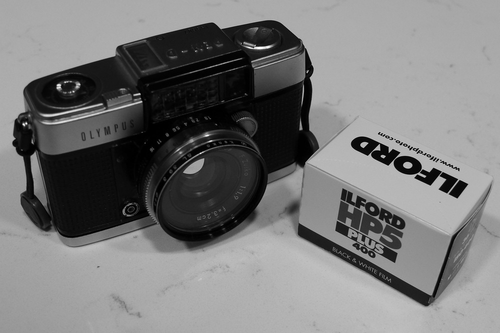 Olympus pen d camera and a box containing a roll of Ilford HP5 Plus film