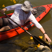 Ed reaches from his kayak to pick up some rubber ducks that were lazily lounging in the shade instead of racing down the canal.
