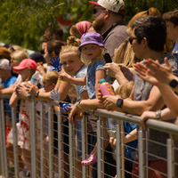 Spectators lining a fence overlooking the canal cheer for the winning duck